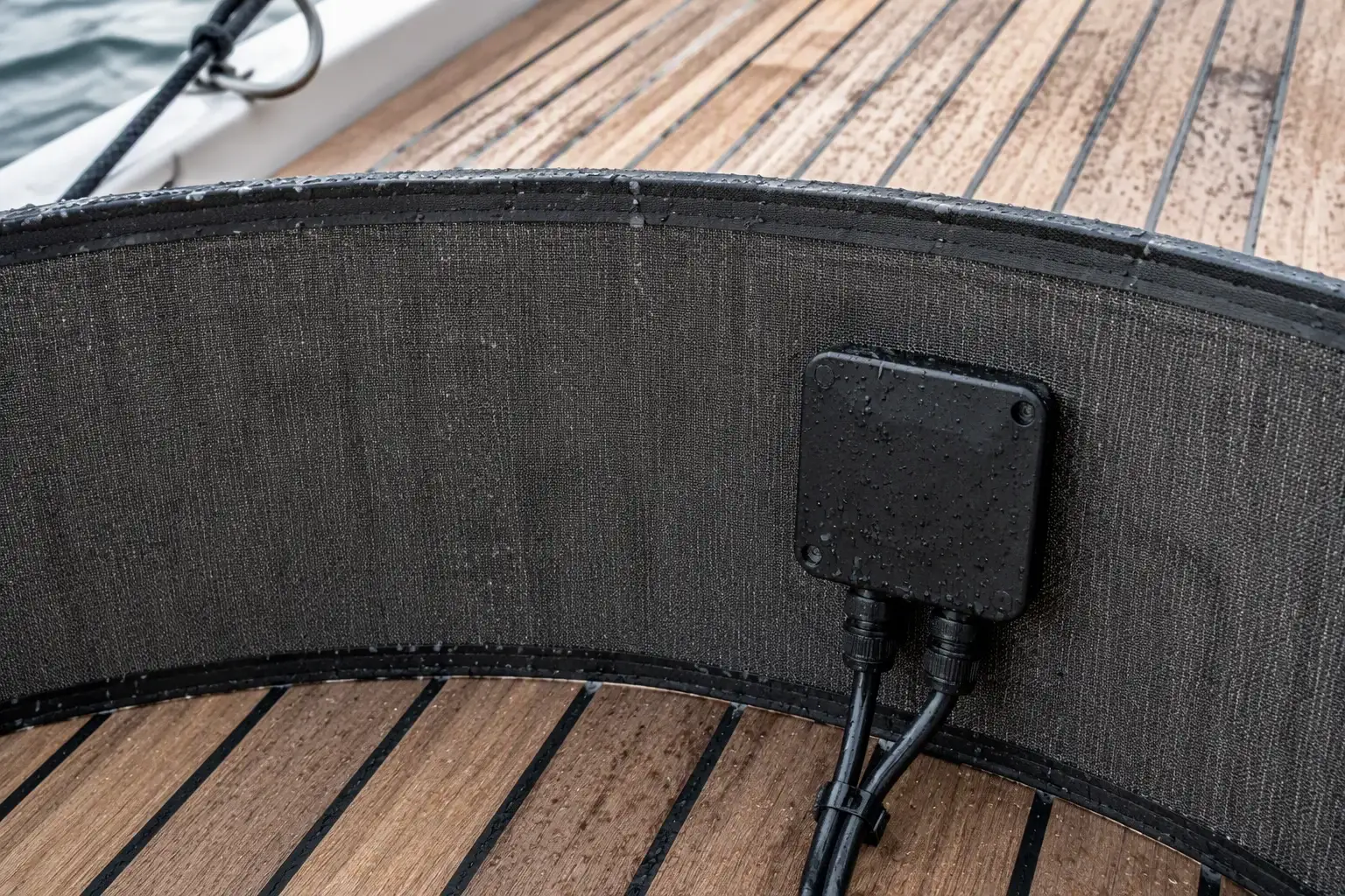 Bent flexible panel with fabric backing on a teak deck